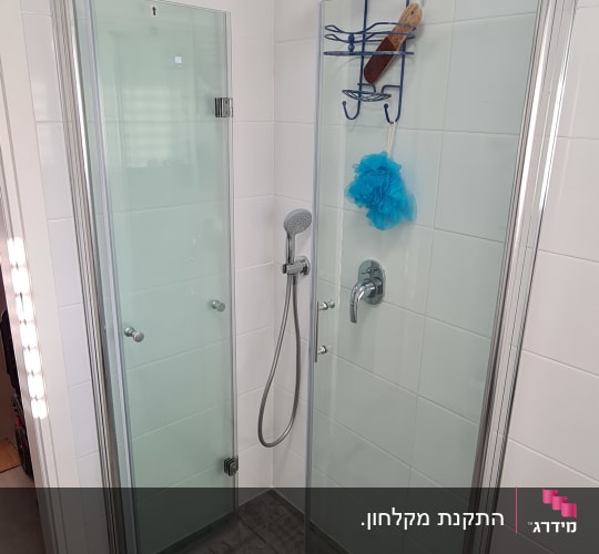 מקלחון פינתי עם דלתות זכוכית בחדר רחצה מרוצף